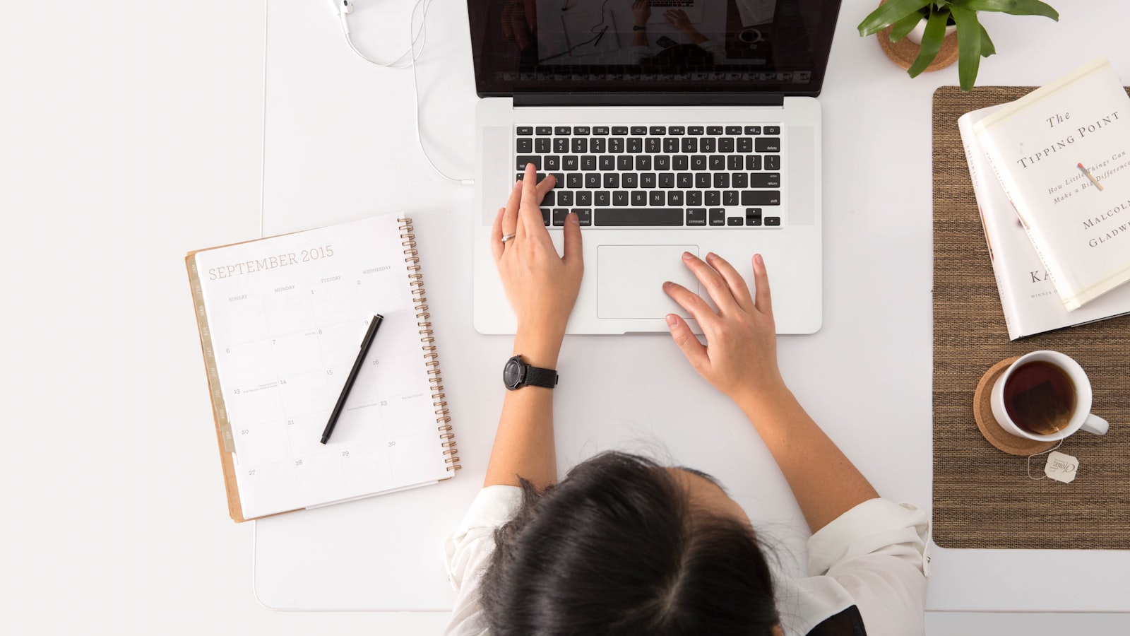 A top-down view of a workspace with a laptop, paper calendar, and notebook — manual property management workflows.